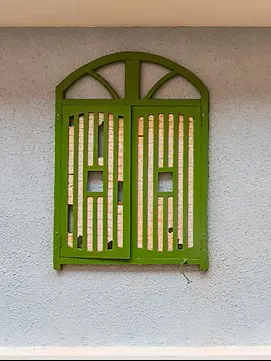 A hand-painted green shuttered window set into a hand-plastered wall